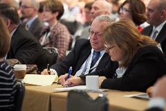 Attendees take notes as speakers share insights for reducing redundancies in care and improving data integration.